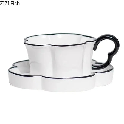 White ceramic mug set with black edged flower design featuring a black rim and heart-shaped handle with matching saucer