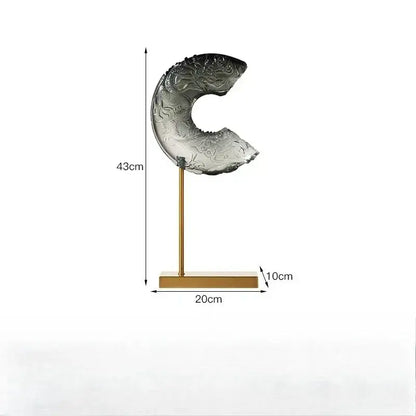 A translucent gray black glass dragon sculpture with intricate carvings on a gold-toned stand decorbites crescent moon decor