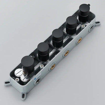 Gray plastic housing with five black knobs and gold threaded ports on the back of a brass thermostatic faucet mixer