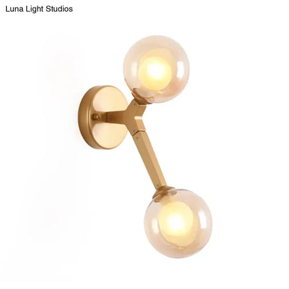 Black and gold bubble wall sconce with two amber glass globes designed as a stylish bedroom glass globe light