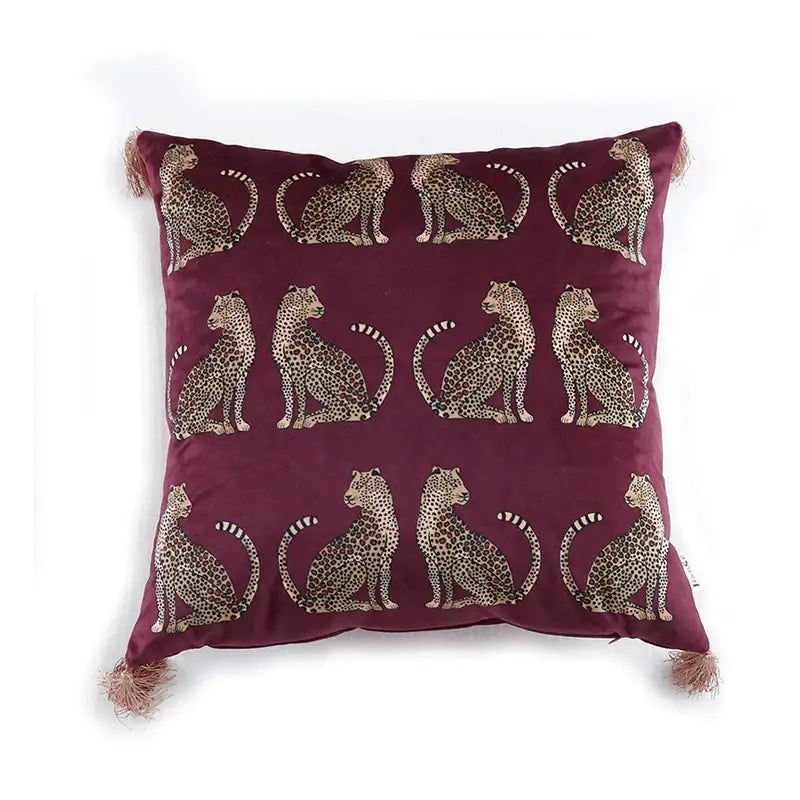 Maroon velvet throw pillow cover with beige and black embroidered seated leopards and matching tassels on corners