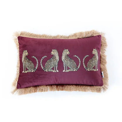 A maroon velvet throw pillow cover with embroidered leopard silhouettes and tan fringe tassels for living room decor