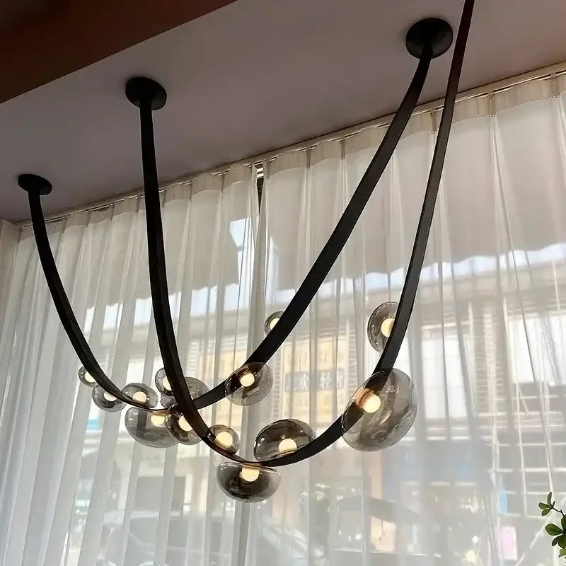 Modern black metal pendant light with curved arms and smoked glass light sources as a dining room focal point