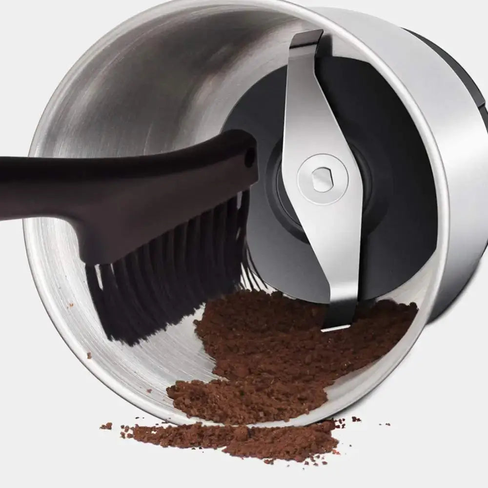 Silver electric coffee grinder with dark brown grounds and black decorbites espresso machine cleaning brush set