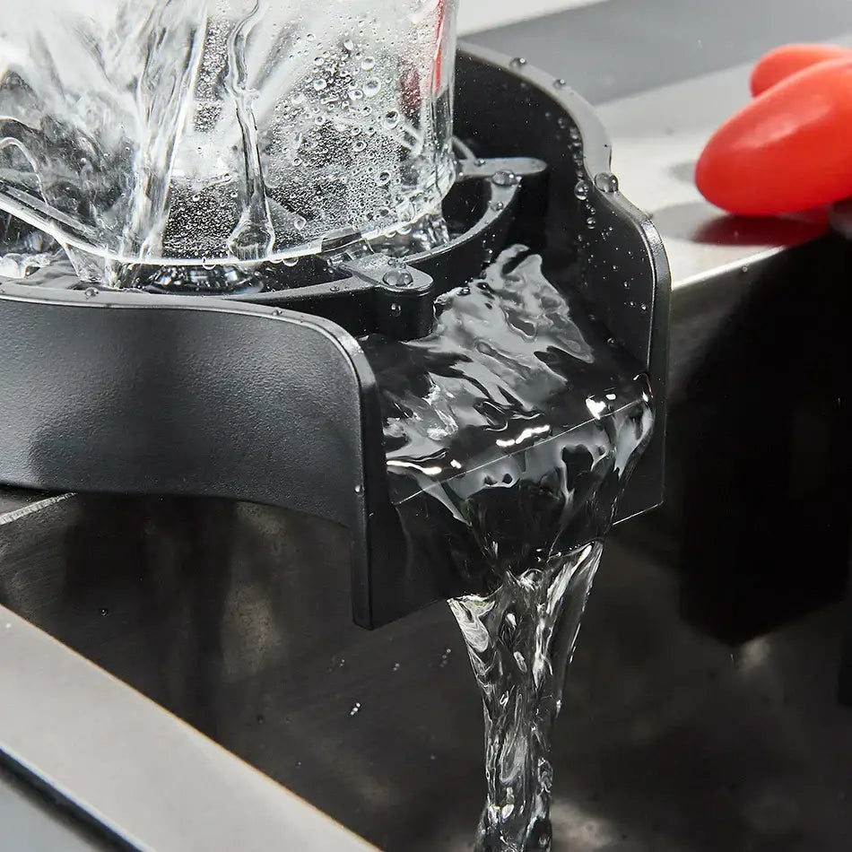 Black plastic glass rinser faucet with clear glass container showing flowing liquid for kitchen sink use