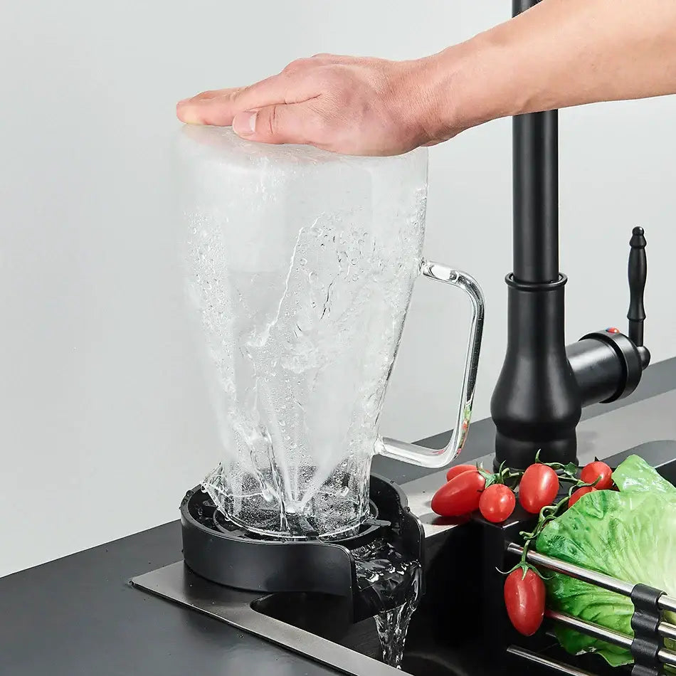 Black plastic glass rinser faucet with sleek handle resting on drip tray as water cascades into the kitchen sink