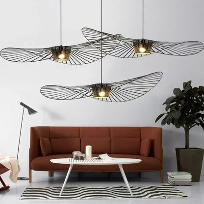 Three black rattan hat led chandelier pendant lights with warm interiors hang above a modern living room decorbites black rattan