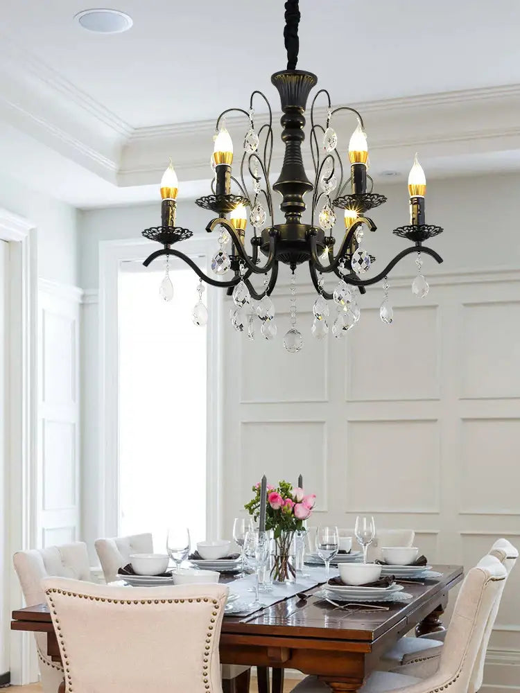 Black wrought iron chandelier with crystal droplets and candle-style bulbs for dining room lighting