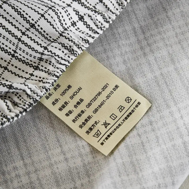 Beige fabric care label with black chinese text and laundry symbols on the back of a decorbites coarse cotton queen fitted sheet
