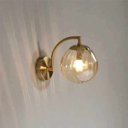 Brass-finished wall lamp with a textured amber-tinted glass globe for bedroom decorbites colored glass ball lighting