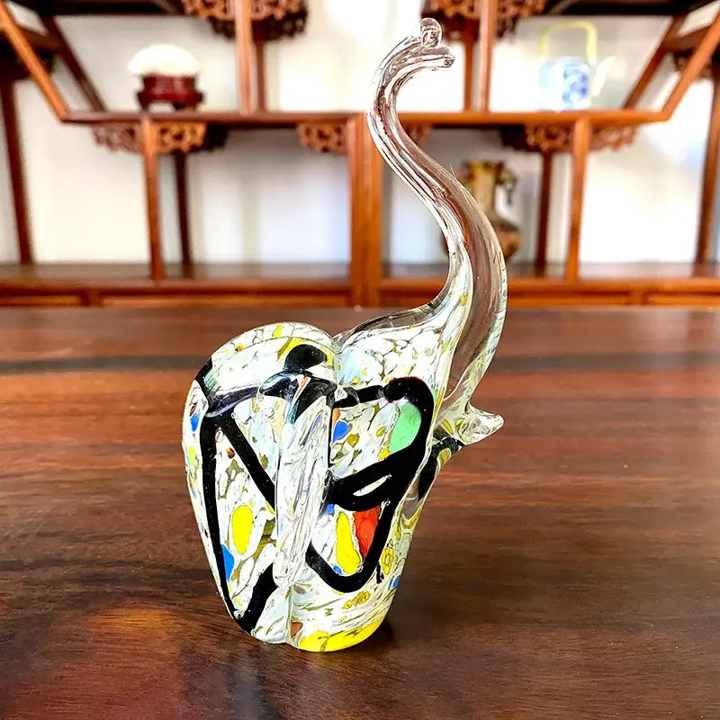 A crystal glass elephant sculpture with a long curved trunk and colorful blue and green abstract patterns for living room decor