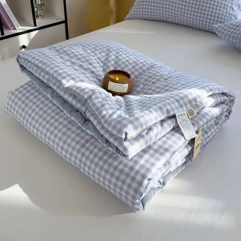 A neatly folded blue and white plaid cotton summer quilt with soybean fiber filling and subtle striped lining