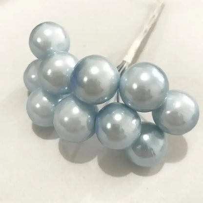 A cluster of light blue glossy pearl-like flower stamen berries attached to a thin metal stem for cake decor