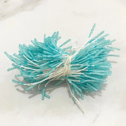 A bundle of turquoise and white sugar-coated candy sticks tied with string for blue flower stamen berries bundle decor