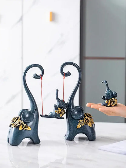 Dark blue ceramic elephant family swing sculpture with gold rose embellishments and curved trunks for living room decor