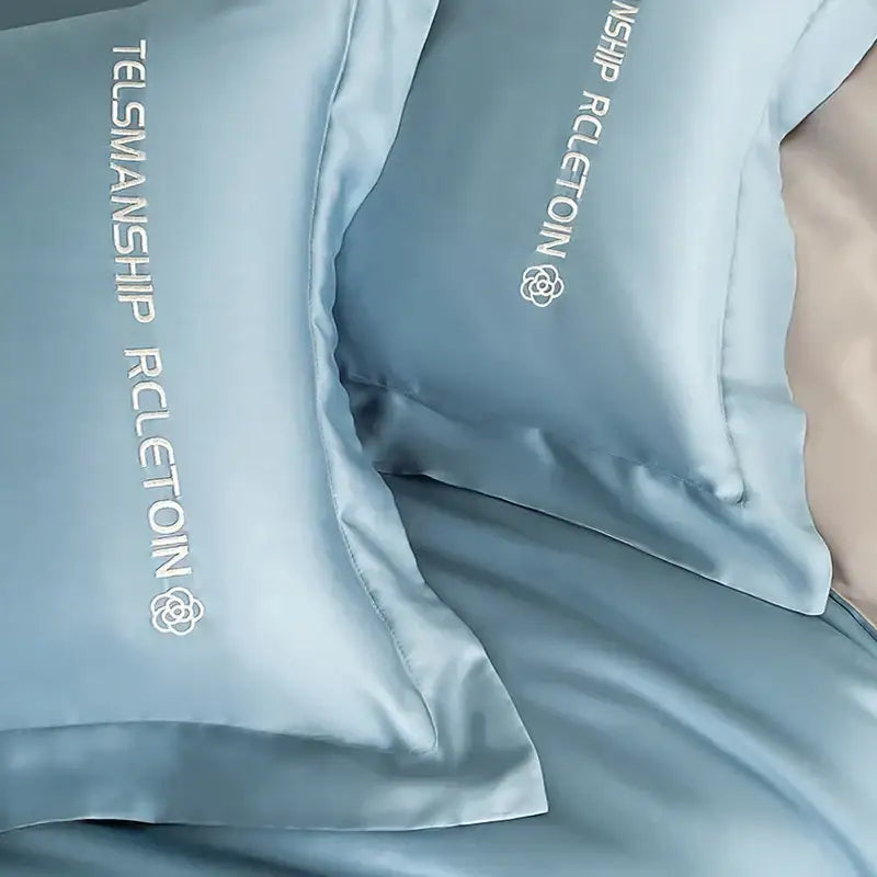 Light blue satin pillowcases with white embroidered text in a decorbites cotton solid color bedding set for bedroom