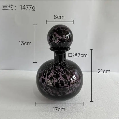 A black glass decanter with a blue marbled leopard print stopper for decorbites leopard print glass vase decor