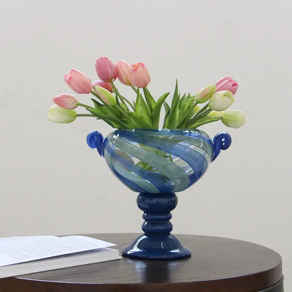 A decorbites blue striped transparent glass vase with swirling patterns holding pink and white tulips for living room decor