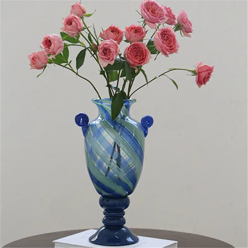 A tall elegant blue striped transparent glass vase with swirling blue and green patterns and dark blue handles for living room decorbites decor