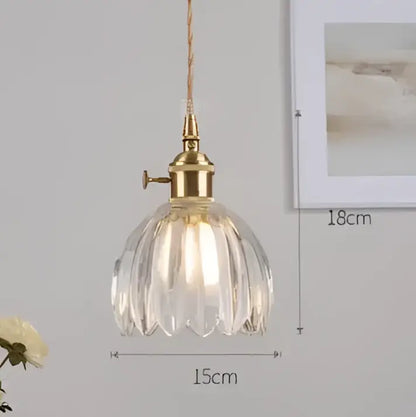 A vintage-style decorbites pendant light with a brass fixture and clear faceted glass shade for bedroom decor