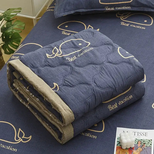 Blue quilted blanket with embroidered whale and best vacation text in gold thread featuring decorbites daisy print quilt design