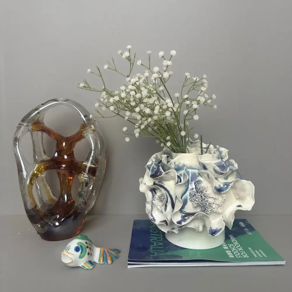 A white ceramic vase with blue glaze and handmade porcelain fold pattern holding delicate white flowers for decorbites decor
