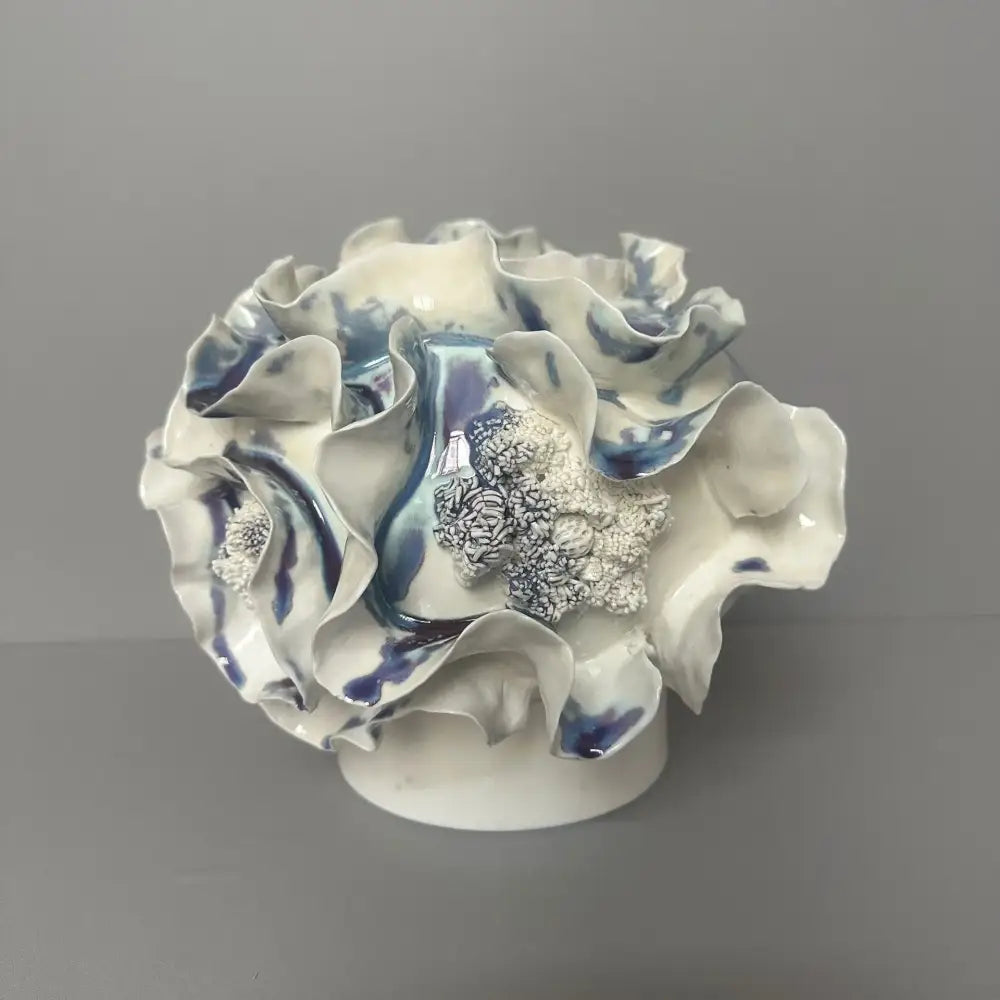 A delicate blue and white decorbites handmade porcelain fold pattern vase with ruffled glaze petals and a silver centerpiece