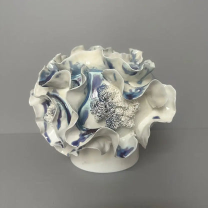 A delicate blue and white decorbites handmade porcelain fold pattern vase with ruffled glaze petals and a silver centerpiece