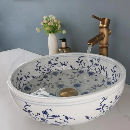 White porcelain basin with blue floral design and gold-toned pop drain in blue and white porcelain basin set