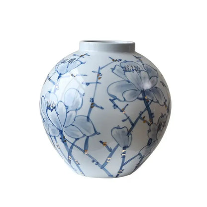 A round white porcelain ceramic vase with blue floral patterns and gold accents for decorbites blue living room decor