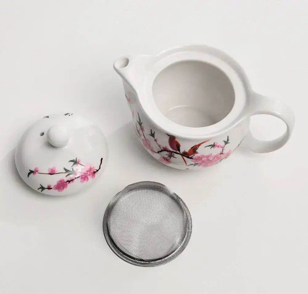 White porcelain tea pot set with pink cherry blossom and red bird designs featuring matching lid and metal strainer