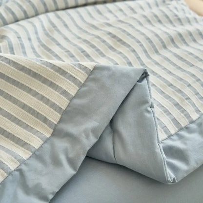 A soft quilted blue and white striped soya fibre decorbites jacquard summer quilt with subtle gray and cream tones