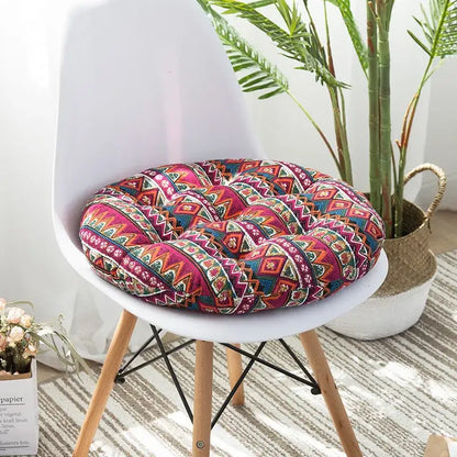 A vibrant bohemian meditation cushion pouf with blue green and red geometric pattern on a white chair