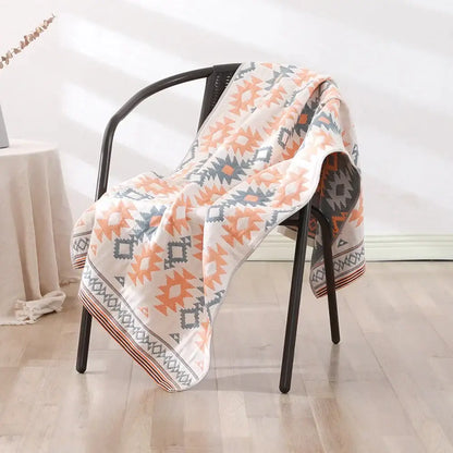 A cozy cream-colored bohemian floral cotton bath towel with vibrant orange and gray geometric border motifs