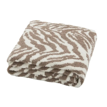 A plush beige and white zebra-striped throw blanket from decorbites bohemian flower knitted collection for bedroom decor