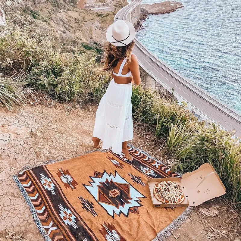 A tan woven bohemian knit throw blanket with brown black and light blue geometric patterns for decorbites decor