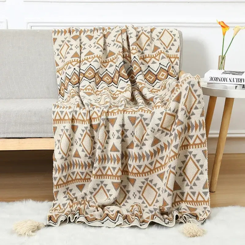 A cozy cream and tan geometric decorbites bohemian knitted sofa blanket with tassels for beige and brown bedroom decor