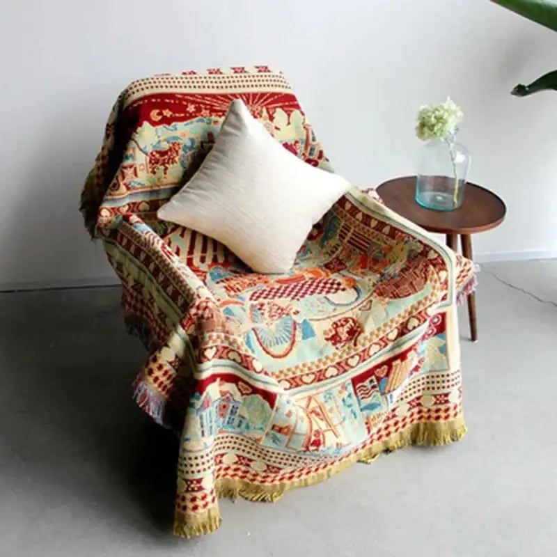 A cozy earth tone bohemian knitted sofa cover with intricate red and cream patterns draped over a chair by decorbites