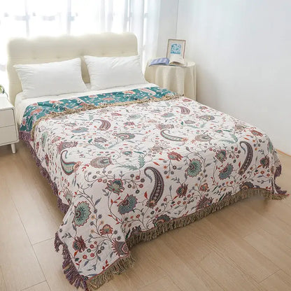 Cream-colored decorbites bohemian sofa blanket with paisley floral patterns in teal rust brown and textured fringe edges