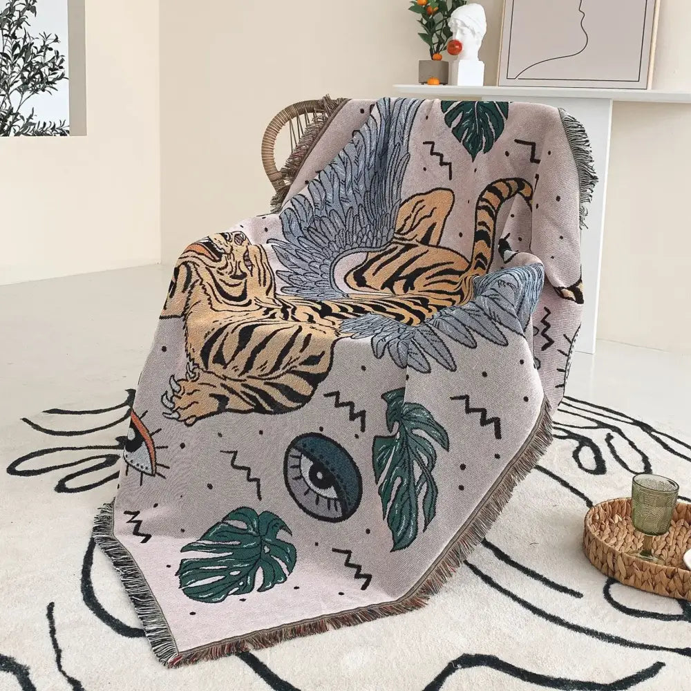 A soft light gray decorbites bohemian outdoor blanket with orange tiger graphic and green monstera leaves for living room decor