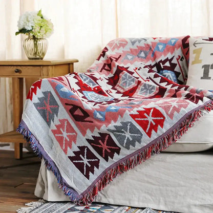 A cozy bohemian pink and red knitted cotton throw blanket with vibrant geometric pattern and fringed edges for decorbites decor