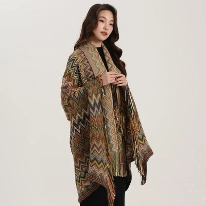 A long open-front knit cardigan in earthy tones with a vibrant zigzag pattern and fringe shawl detailing