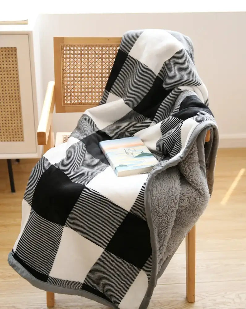 A cozy black and white plaid bohemian winter blanket with soft gray fleece lining for living room use