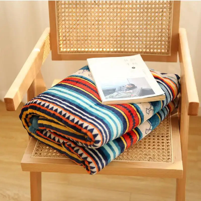 A cozy bohemian winter blanket in multicolored fleece with bold stripes and black triangular patterns for living room