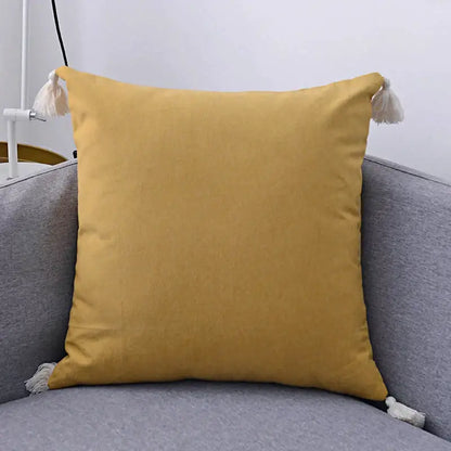 Boho beige linen pillow cover set featuring a mustard-yellow textured pillow cover with white tassels for living room sofa