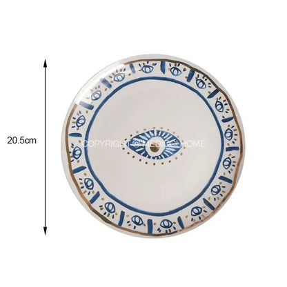A white boho blue and gold bright eyes ceramic dinner plate with central eye motif and decorative borders for dining room decorbites bright eyes