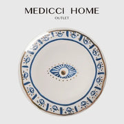 A white ceramic boho bright eyes ceramic dinner plate with blue and gold eye motifs from medicci home decorbites bright eyes