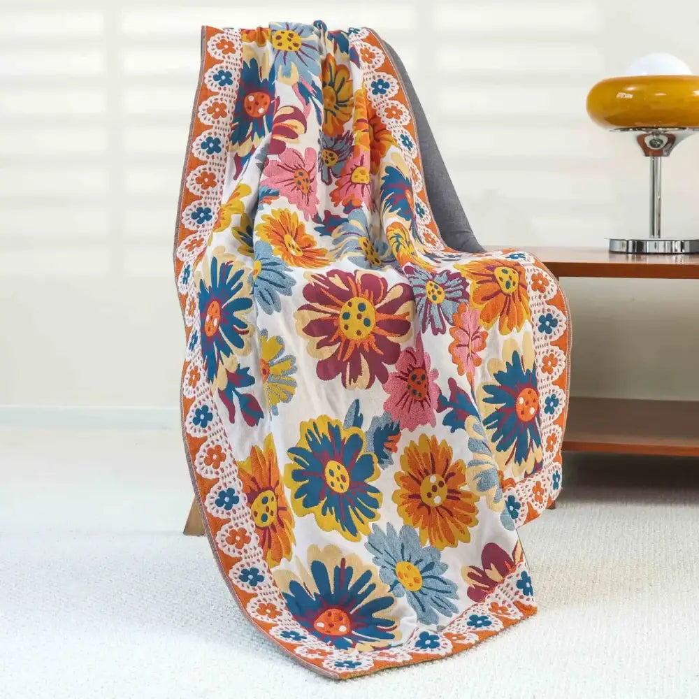 A decorbites boho cotton gauze bath towel featuring a vibrant floral pattern with orange blue and pink blossoms on cream