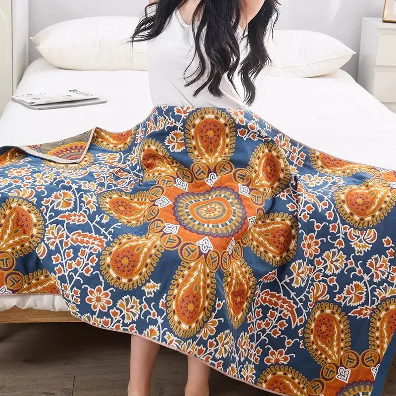A cozy blue bath towel with vibrant orange and white paisley patterns made of decorbites boho cotton gauze