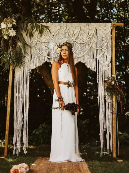 A woman stands beneath a cream cotton macrame wedding backdrop featuring an ornate decorbites cotton macrame design